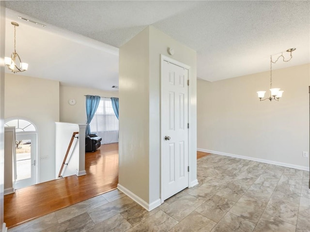 interior space with an upstairs landing, a notable chandelier, a textured ceiling, and baseboards