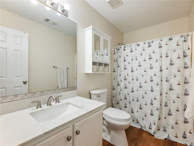 full bathroom featuring visible vents, toilet, wood finished floors, and a textured ceiling