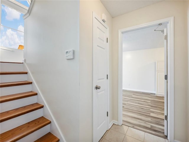 stairway with baseboards and tile patterned flooring