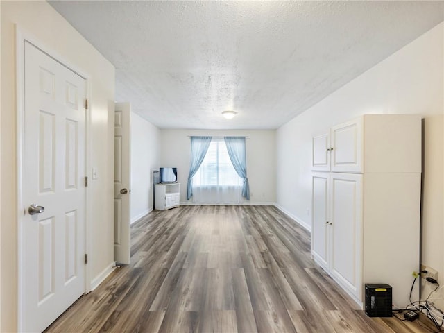 spare room featuring a textured ceiling, baseboards, and wood finished floors