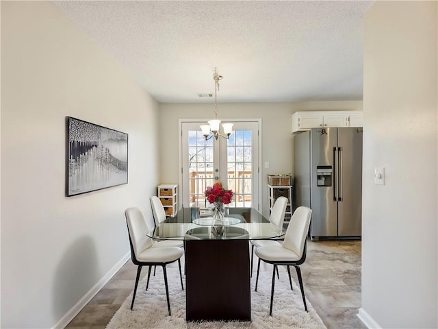 dining space with a notable chandelier, visible vents, a textured ceiling, and baseboards