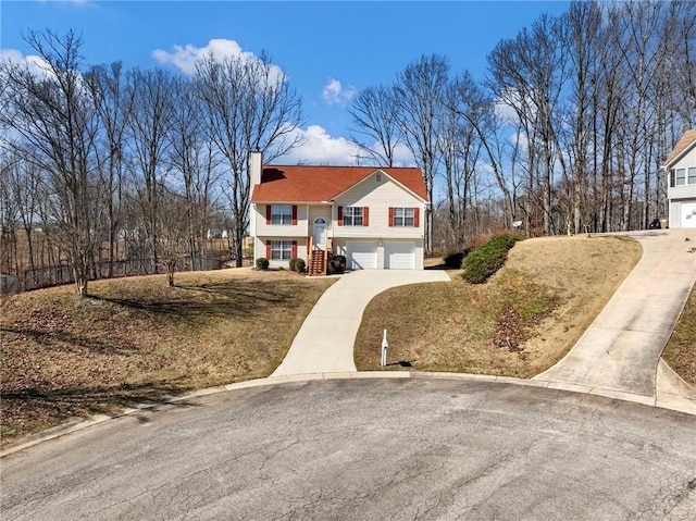 view of front of home featuring a garage, driveway, a front yard, and a chimney