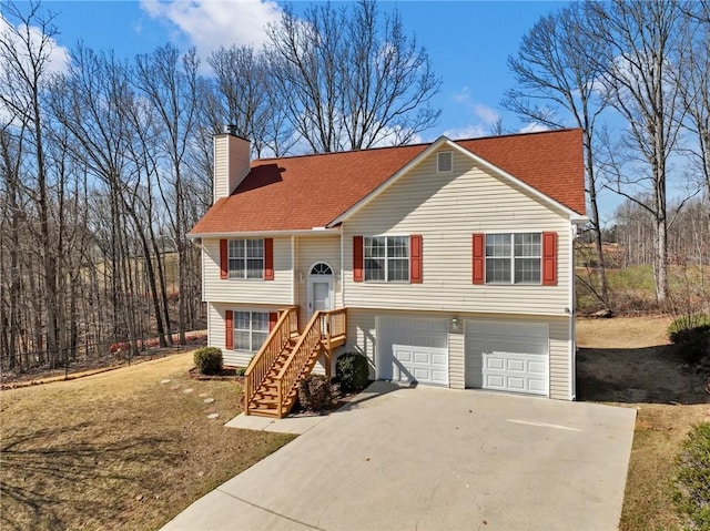 raised ranch featuring an attached garage, driveway, and a chimney