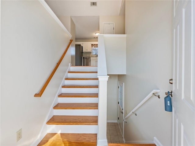 staircase with tile patterned floors and visible vents