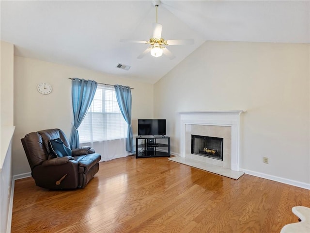 interior space featuring visible vents, a ceiling fan, wood finished floors, a premium fireplace, and vaulted ceiling