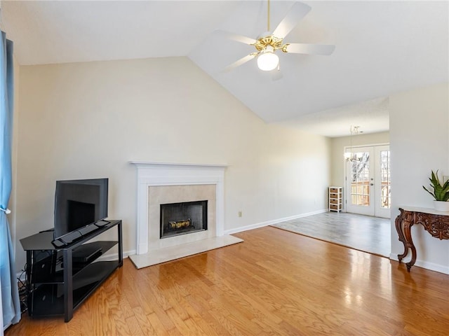 living room with a ceiling fan, wood finished floors, french doors, a fireplace, and vaulted ceiling