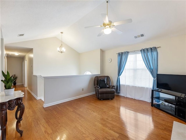 living area featuring visible vents, baseboards, lofted ceiling, and wood finished floors