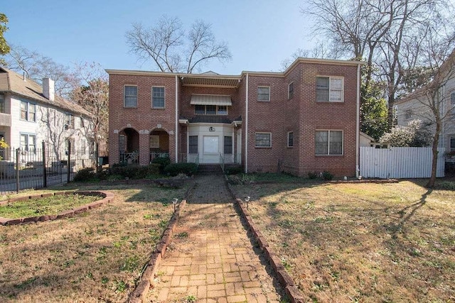 multi unit property with brick siding, a front yard, and fence