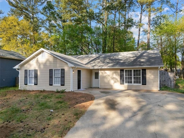 ranch-style home featuring driveway and fence