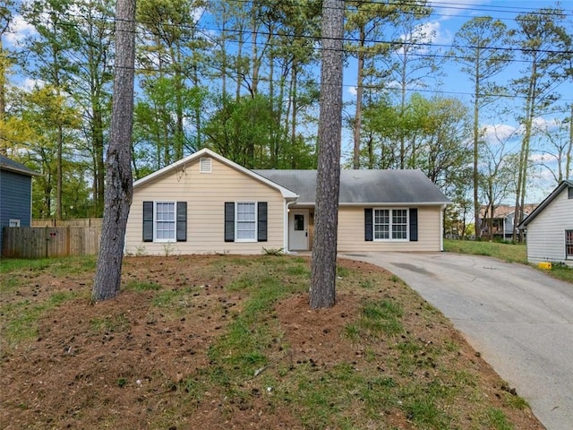 ranch-style home featuring fence and concrete driveway