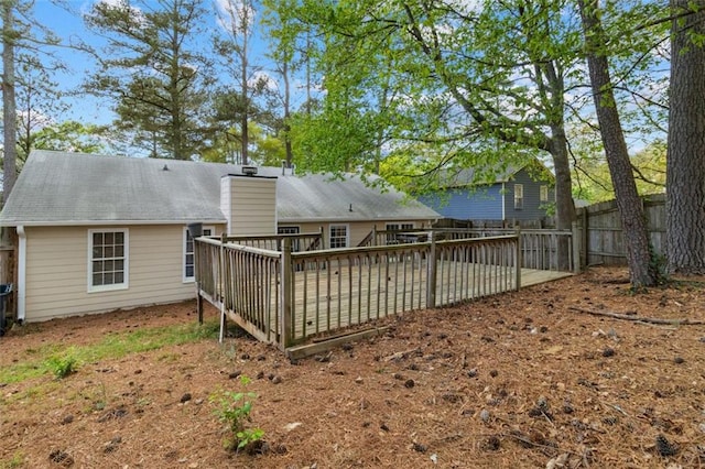 rear view of property featuring a chimney, a deck, and fence