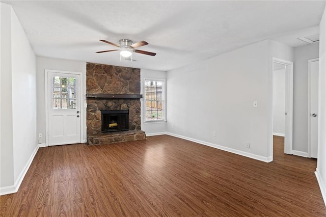unfurnished living room with dark wood-type flooring, ceiling fan, baseboards, and a stone fireplace