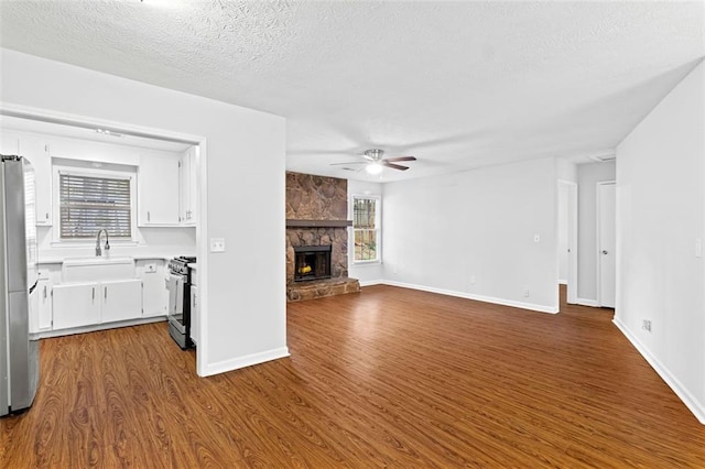 2199 Summertown Dr, Norcross, GA 30071 - unfurnished living room featuring a sink, dark wood-type flooring, a ceiling fan, a textured ceiling, and a fireplace