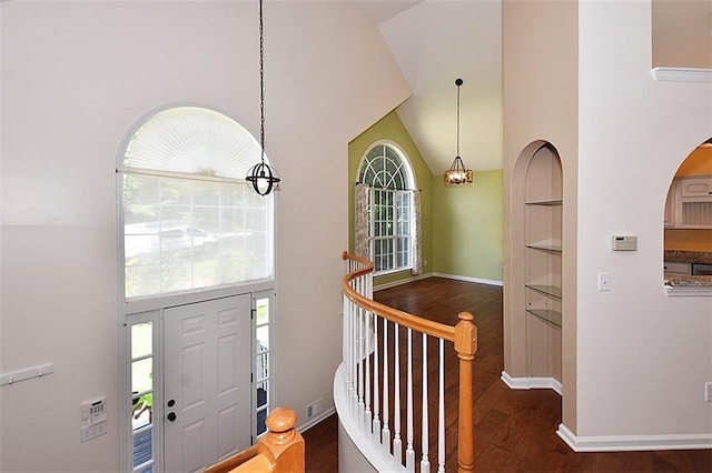 foyer entrance with dark hardwood / wood-style flooring, high vaulted ceiling, and a chandelier