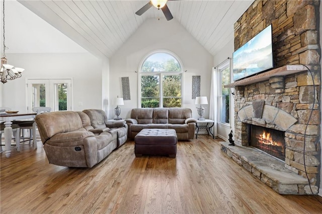 living room featuring a fireplace, light wood-type flooring, and high vaulted ceiling