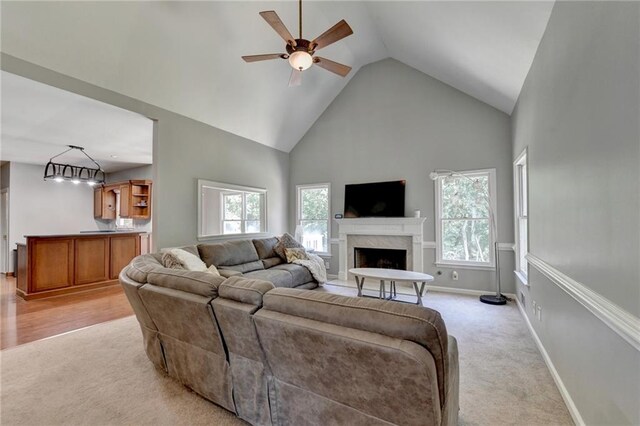 carpeted living room featuring a premium fireplace, high vaulted ceiling, and ceiling fan