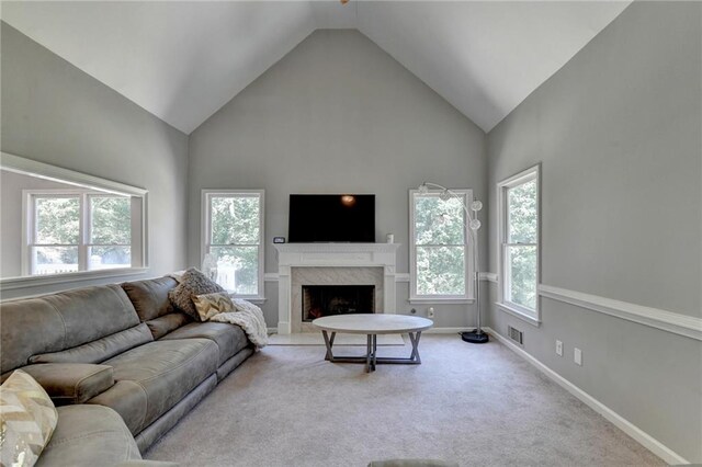 living room featuring light carpet, a premium fireplace, and high vaulted ceiling