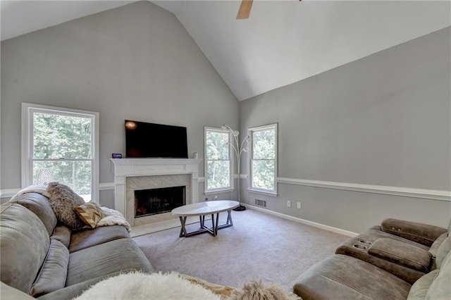 living room featuring high vaulted ceiling, light colored carpet, a high end fireplace, and ceiling fan