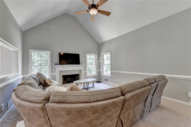 carpeted living room featuring a premium fireplace, a healthy amount of sunlight, high vaulted ceiling, and ceiling fan