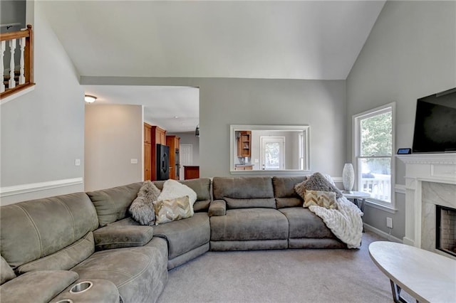 living room with light colored carpet, a high end fireplace, and vaulted ceiling