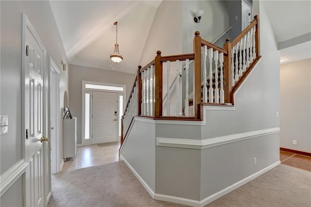 entrance foyer featuring high vaulted ceiling and light colored carpet