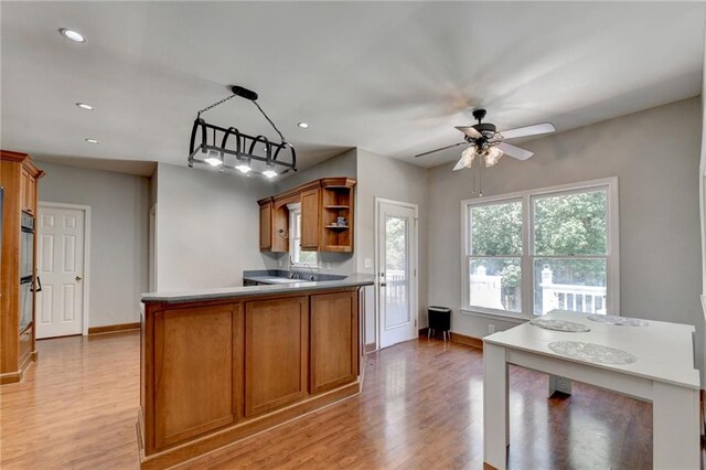 kitchen featuring light wood-type flooring, pendant lighting, double wall oven, and ceiling fan