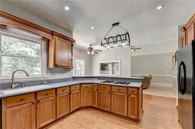 kitchen featuring light wood-type flooring, kitchen peninsula, sink, ceiling fan, and appliances with stainless steel finishes