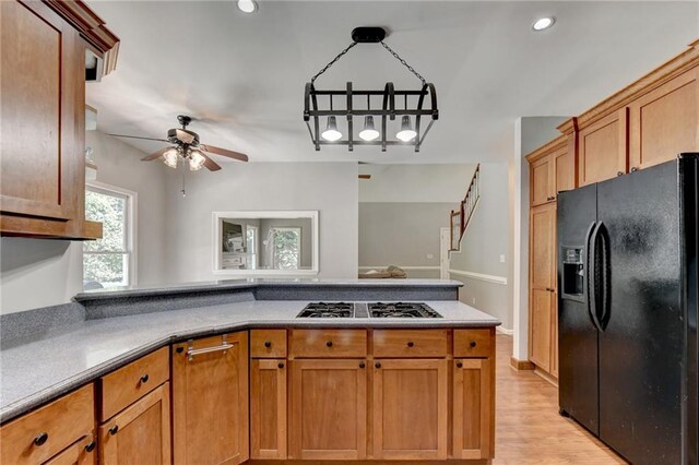 kitchen featuring ceiling fan, light wood-type flooring, stainless steel gas stovetop, and black fridge with ice dispenser