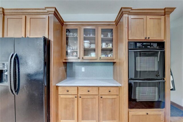 kitchen with black appliances, light brown cabinetry, and backsplash