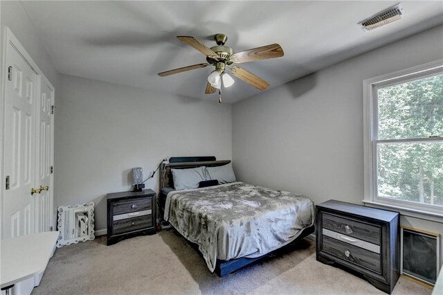 bedroom with multiple windows, light colored carpet, and ceiling fan