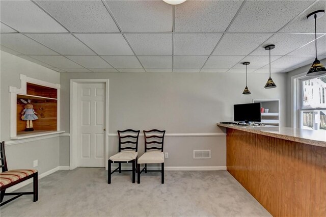 living area featuring a paneled ceiling and carpet