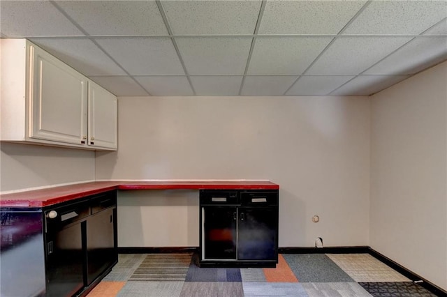 kitchen featuring a paneled ceiling, carpet flooring, and white cabinetry