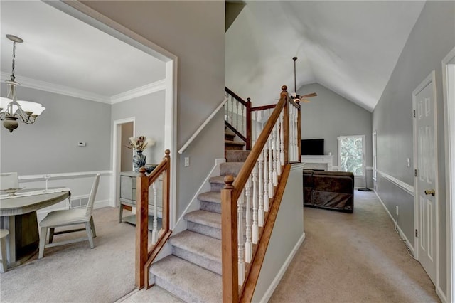 stairs with crown molding, vaulted ceiling, ceiling fan with notable chandelier, and carpet floors