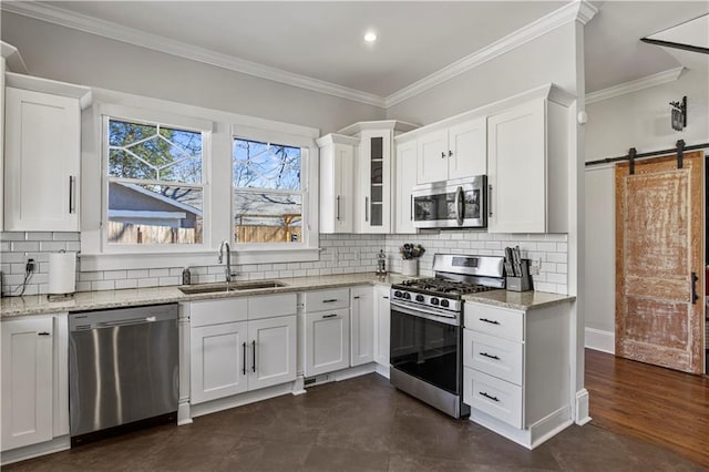 kitchen with a sink, stainless steel appliances, a barn door, and white cabinets