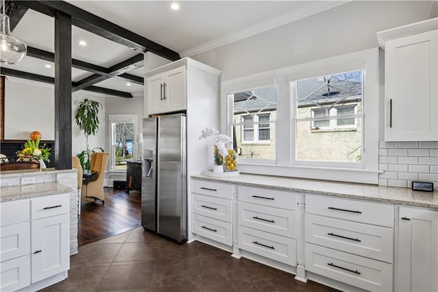 kitchen featuring decorative backsplash, stainless steel fridge, beamed ceiling, and white cabinetry