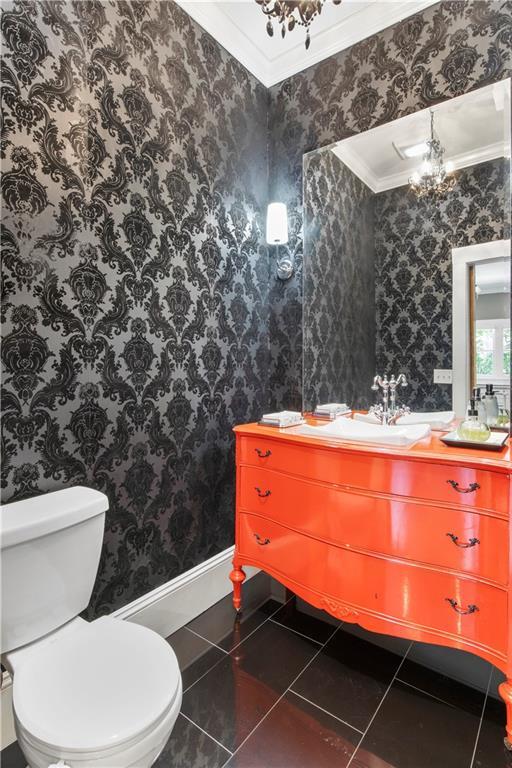 half bathroom featuring an inviting chandelier, ornamental molding, and wallpapered walls