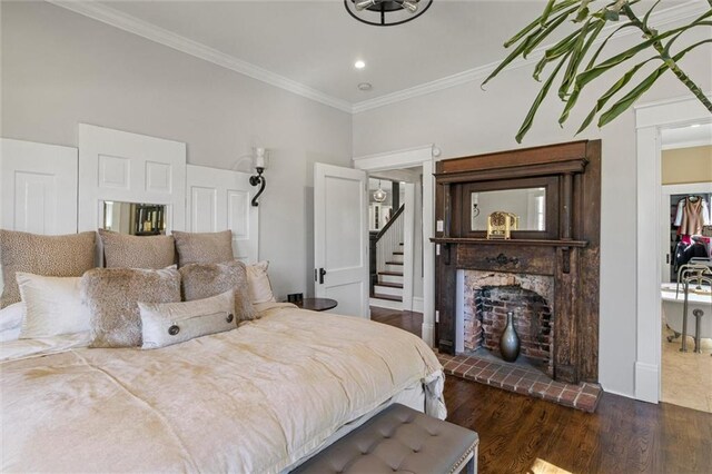 bedroom with a fireplace, crown molding, and wood finished floors