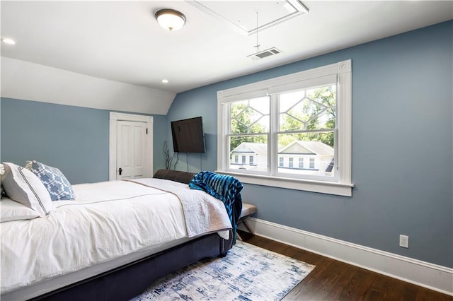 bedroom featuring visible vents, lofted ceiling, wood finished floors, baseboards, and attic access