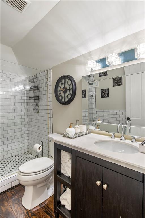 full bath featuring visible vents, toilet, wood finished floors, a shower stall, and vanity