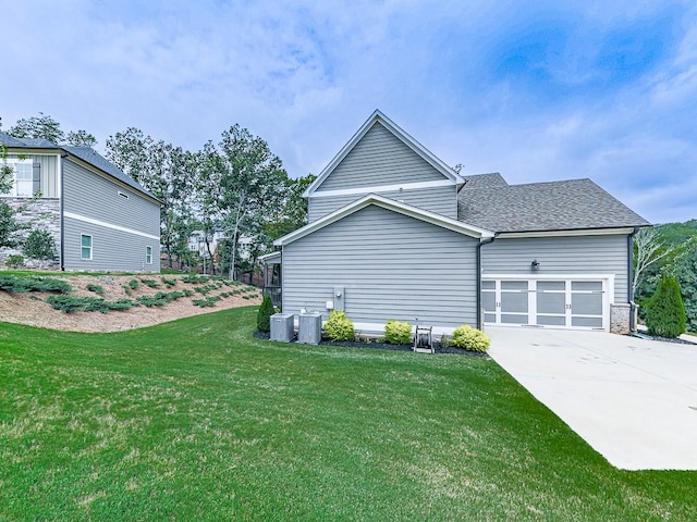 view of home's exterior featuring a garage, roof with shingles, a lawn, and driveway