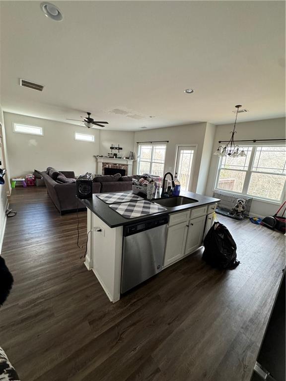 240 Sugar Maple Dr, Cornelia, GA 30531 - kitchen featuring stainless steel dishwasher, dark countertops, a brick fireplace, open floor plan, and dark wood-style flooring