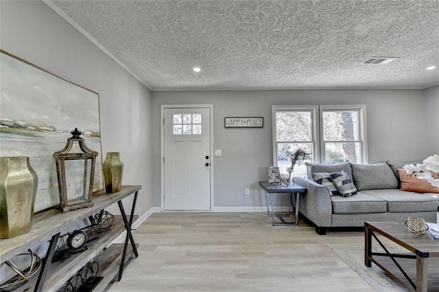 interior space featuring a textured ceiling, light hardwood / wood-style floors, and crown molding