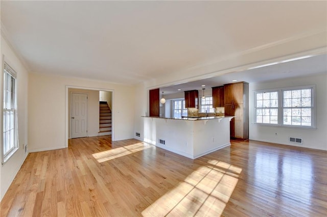 unfurnished living room featuring plenty of natural light and light hardwood / wood-style flooring