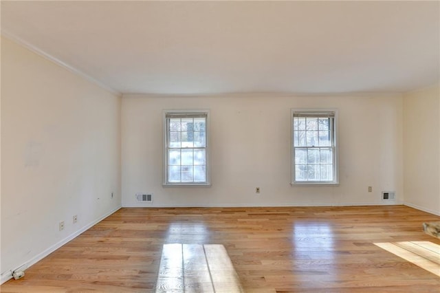 empty room featuring light hardwood / wood-style flooring, plenty of natural light, and ornamental molding