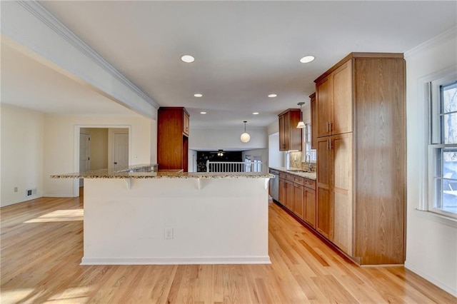 kitchen with sink, dishwasher, a kitchen breakfast bar, light stone counters, and light hardwood / wood-style floors