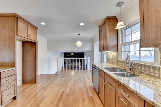 kitchen with stainless steel dishwasher, decorative light fixtures, light stone countertops, and sink