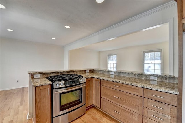 kitchen with light stone countertops, gas stove, kitchen peninsula, and light wood-type flooring