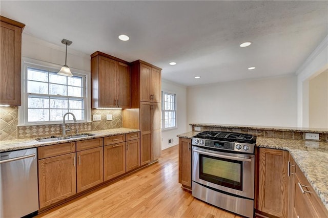 kitchen featuring sink, appliances with stainless steel finishes, ornamental molding, light stone countertops, and decorative light fixtures