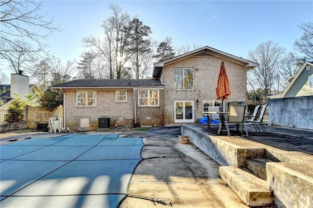 back of house featuring a covered pool, a patio, and central air condition unit