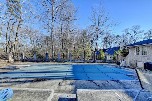 view of swimming pool featuring a patio, a diving board, and cooling unit